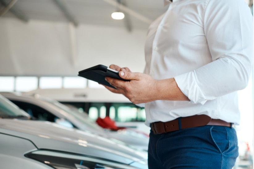 Man holding tablet in a car dealership